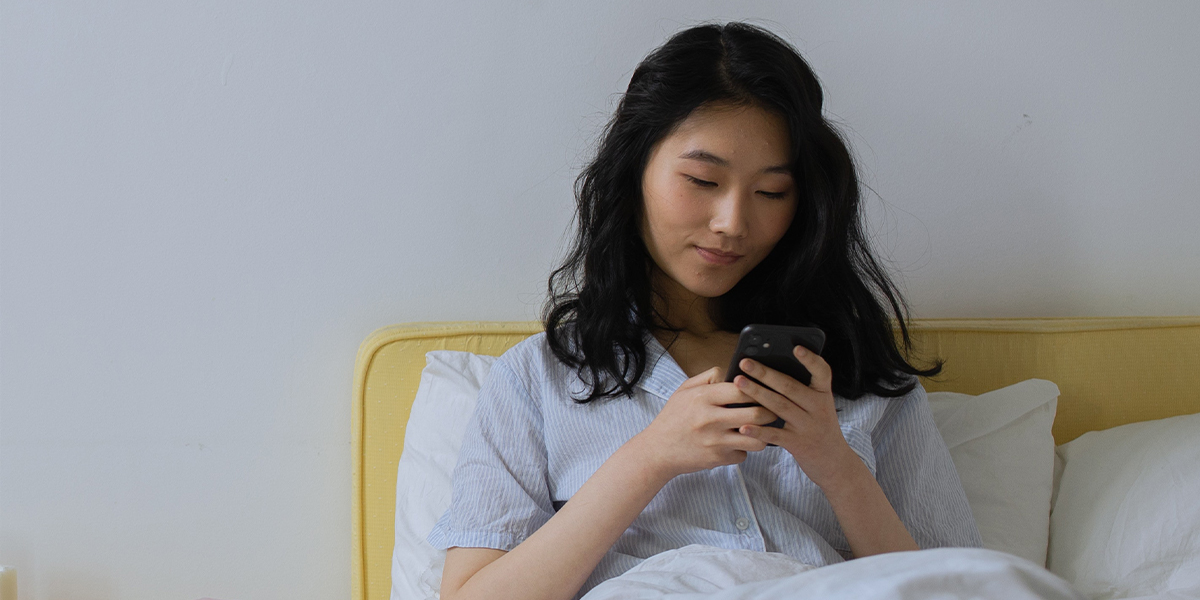 Kvinne bruker PatientSky på mobilen i sengen