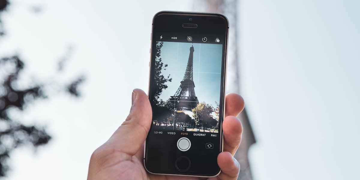Hånd holder mobil som tar bilde av Eiffeltårnet