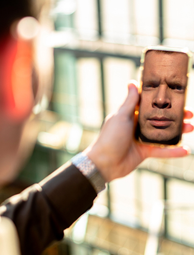Thorbjørn Busch som ser eget speilbilde i mobilen