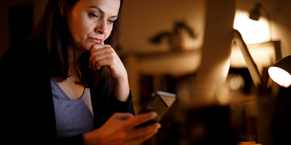 kvinne ser på mobil bekymret falsk nettside