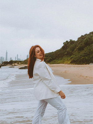 Kvinne som poserer i hvit dress på en strand