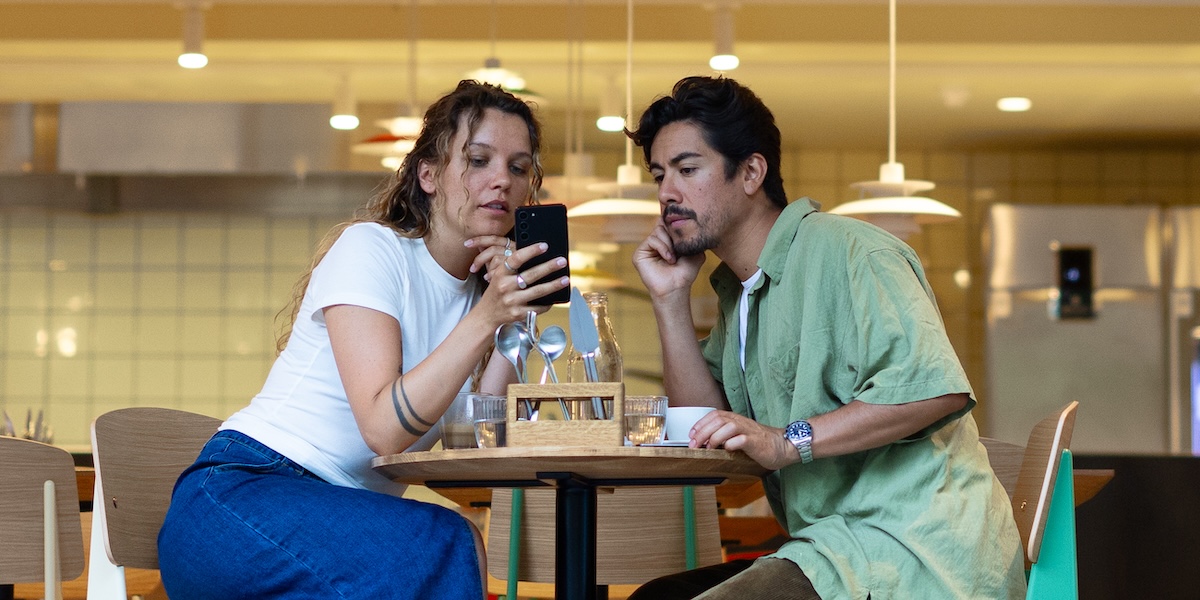 Mann og kvinne sitter på café og surfer på mobil