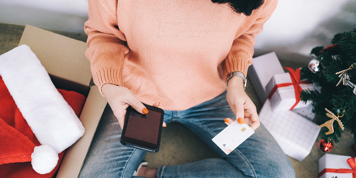 Kvinne med mobil og kredittkort som ser på falske nettbutikker