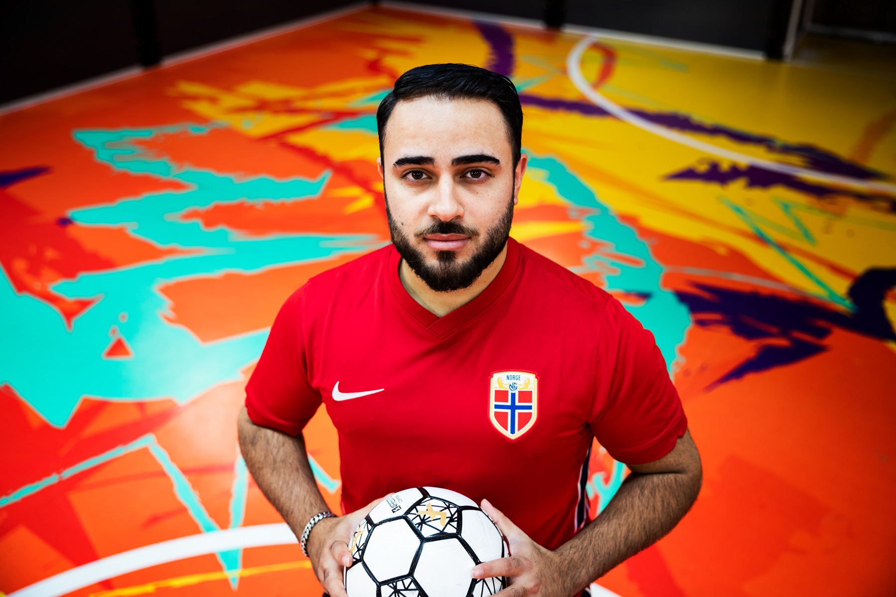 Bilde av Arkan som står inne på en fargerik fotballbane i Oslo Street Football Center