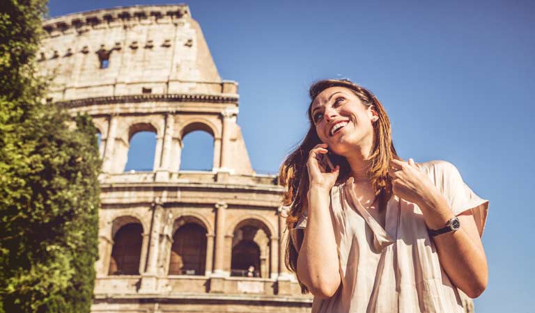 Dame som snakker i mobilen utenfor Colosseum i Roma